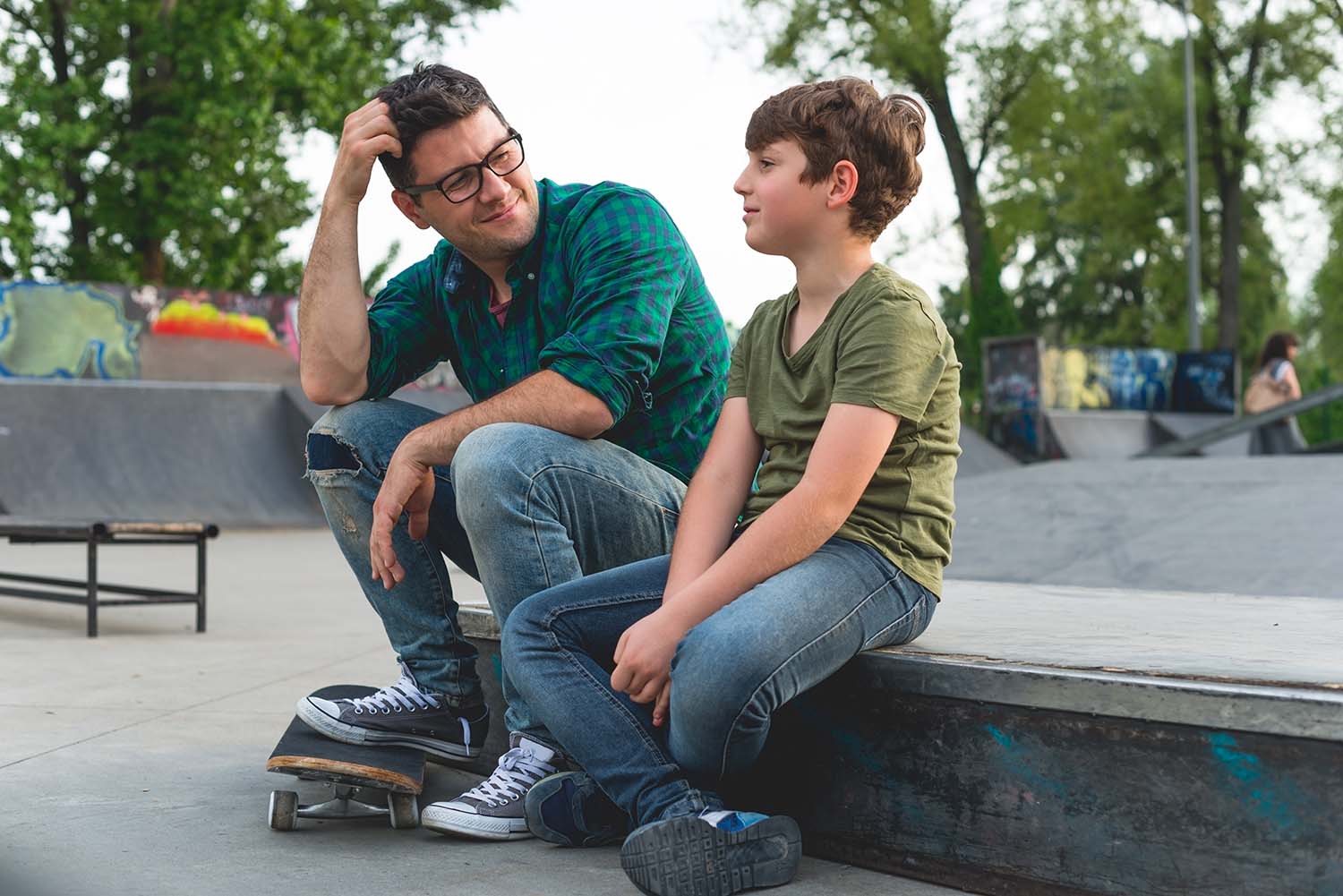 father and child sitting at a skate park talking