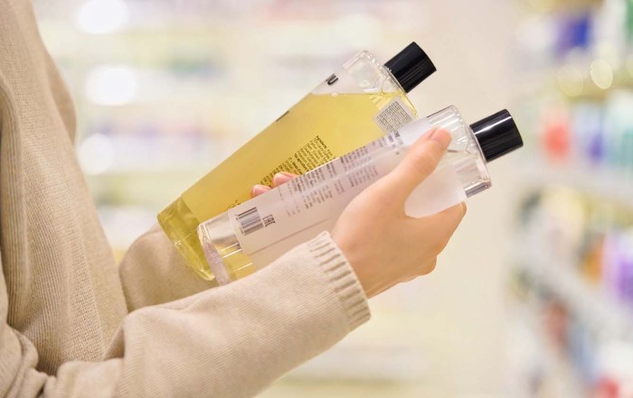 A woman holding two bottle of shampoo in a store