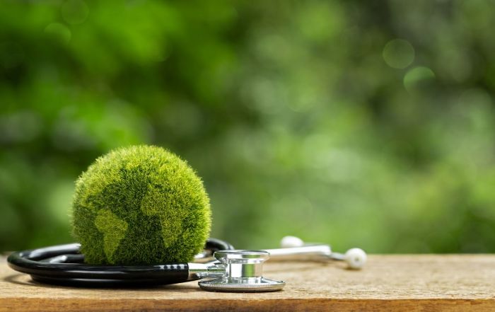 A stethoscope wrapped around a fuzzy green earth, representing the importance of sustainability in the healthcare industry.